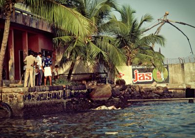 Un groupe d'homme regardent un cadavre échoué devant le carrelets de pêcheurs à Cochin.