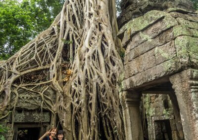 2 jeunes femmes prennent la pose devant un temple envahi par les racines à Angkor au Cambodge