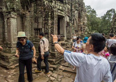 Touristes asiatiques se prenant en photo dans un temple à Angkor au Cambodge